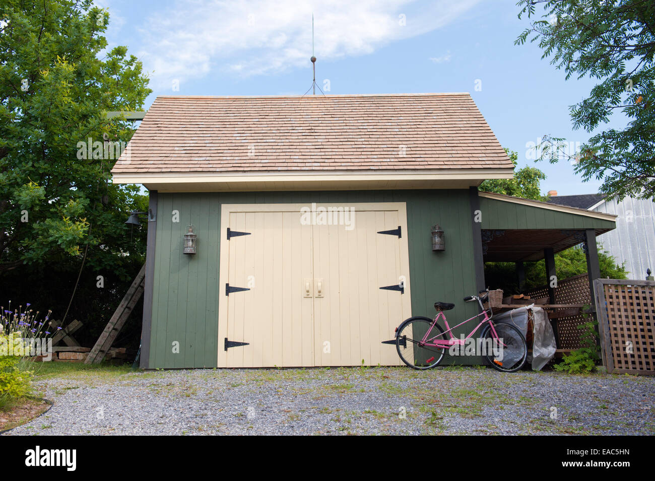 Rosa Fahrrad gegen eine grüne und gelbe Holz Garage gestützt. Stockfoto