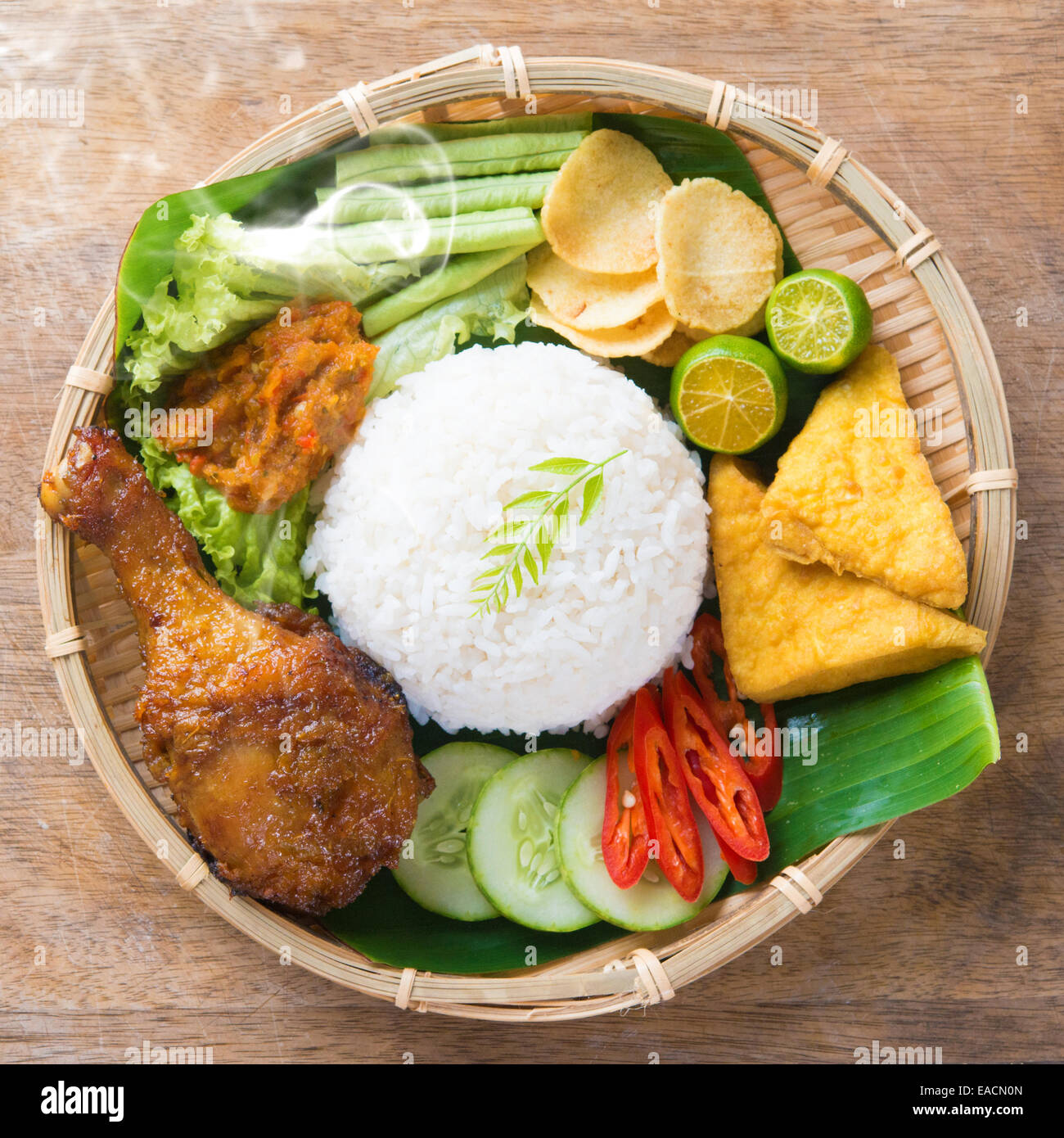 Berühmte traditionelle indonesische Speisen. Köstliches Nasi Ayam Penyet mit Sambal Belacan. Frisch heiß mit Dampf Rauch. Stockfoto