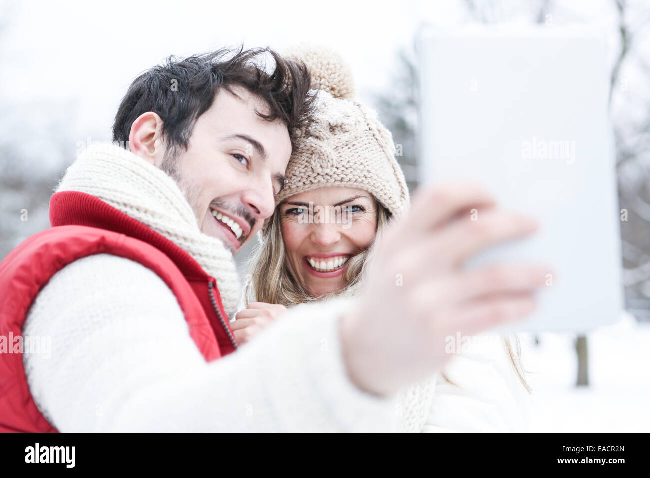 Glückliches Paar im Winterurlaub unter tablet Computerbilder Stockfoto