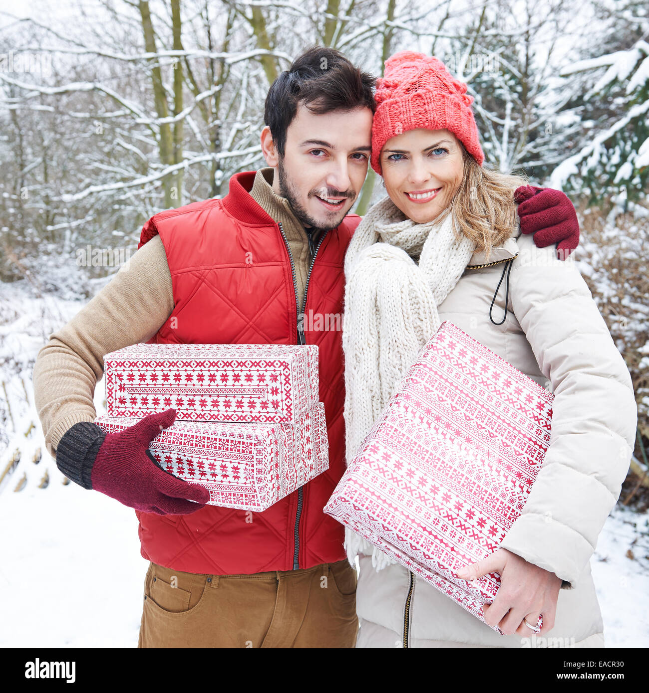 Brautpaar mit Weihnachtsgeschenke im Winter stehen im Schnee Stockfoto