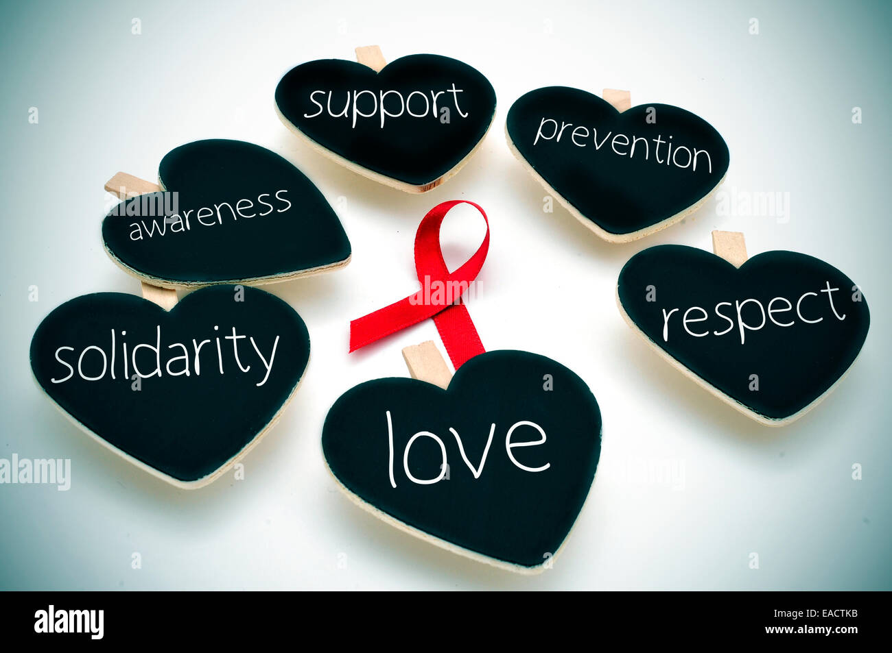 ein rotes Band für den Kampf gegen AIDS und einige herzförmige Tafeln mit Worten solche Unterstützung, Prävention, Respekt, Liebe, so Stockfoto