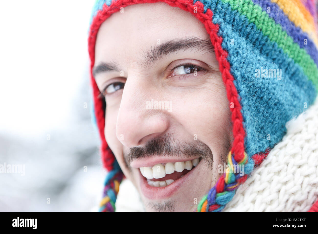 Glücklich lächelnd im Winter mit einem bunten Wollkappe Jüngling Stockfoto