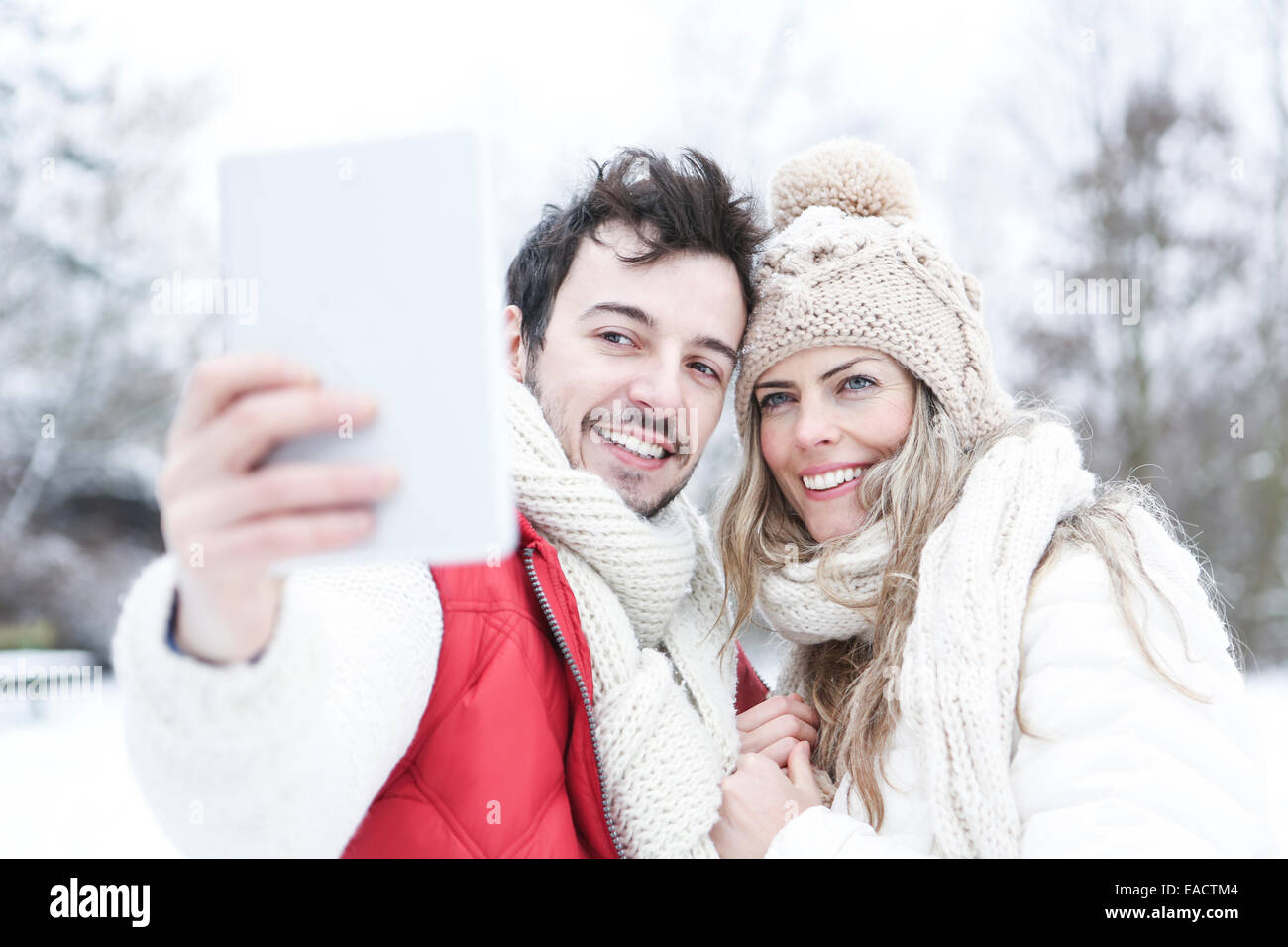 Glückliches Paar im Winter fotografieren sich mit Tablet-PC Stockfoto