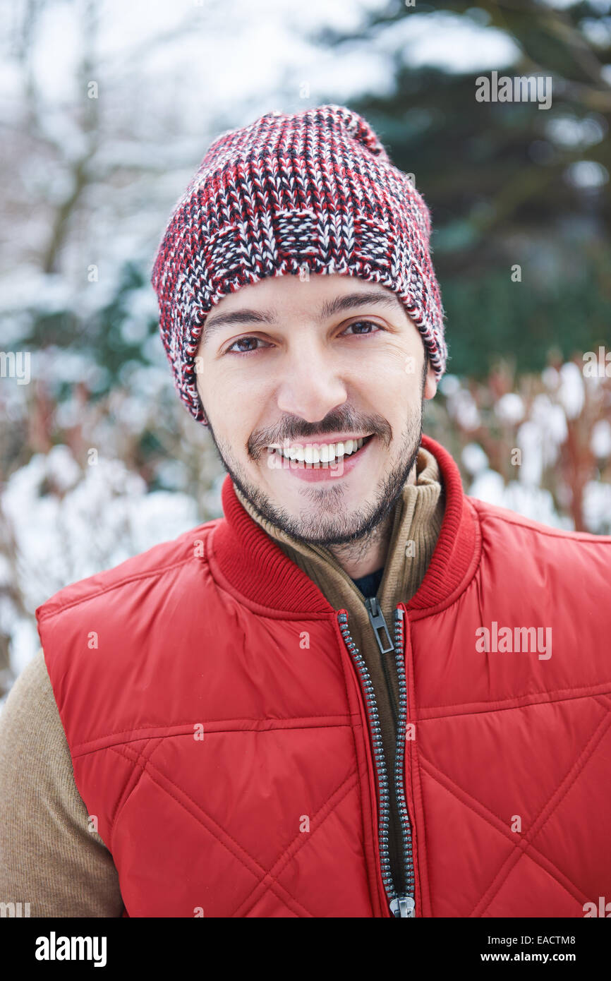 Glücklich attraktiver Mann mit Mütze im Winter stehen im Schnee Stockfoto