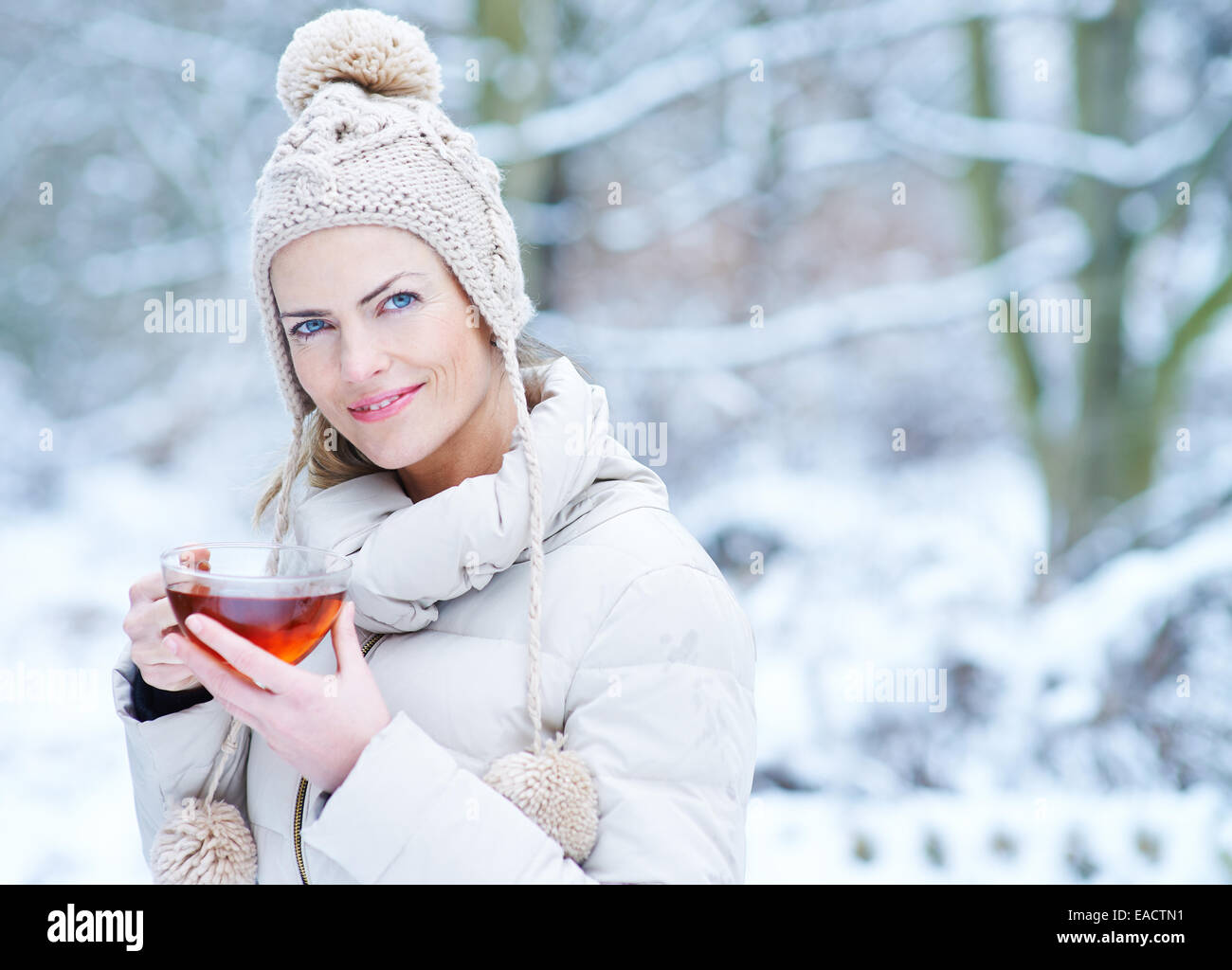 Lächelnde Frau trinken Sie eine Tasse schwarzen Tee im winter Stockfoto