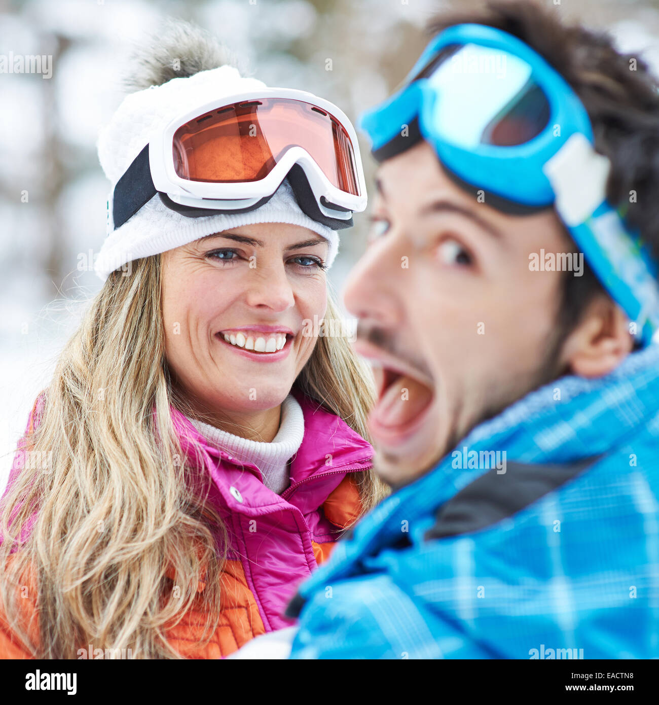 Lächelnde Paare, die Spaß in einem Ski-Reise-Urlaub im Schnee Stockfoto