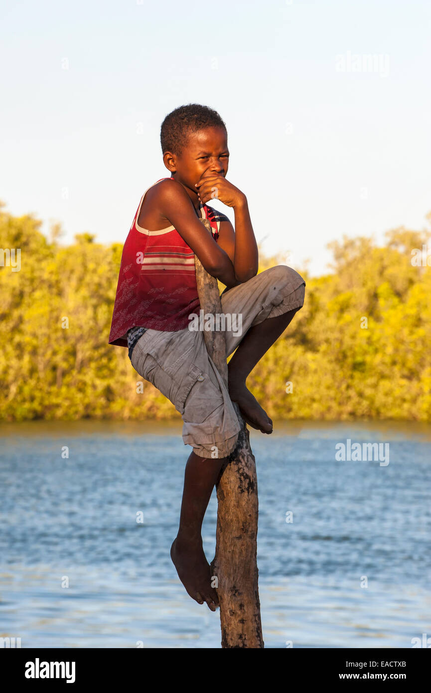 Madagassische Junge sitzt auf einem Mast, Morondava, Toliara Provinz, Madagaskar Stockfoto