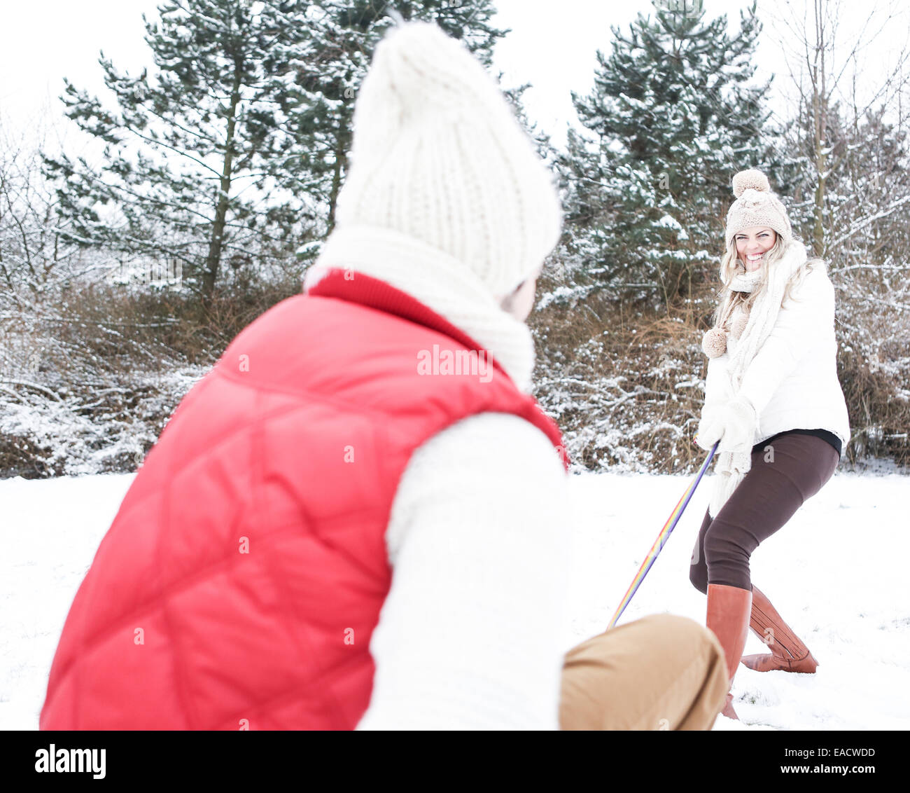 Frau Mann auf Schlitten im Winter durch Schnee ziehen Stockfoto