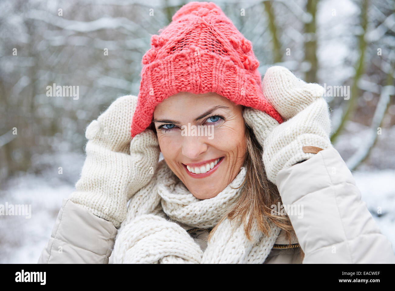 Lächelnde Frau im Winter Mütze auf den Kopf setzen Stockfoto