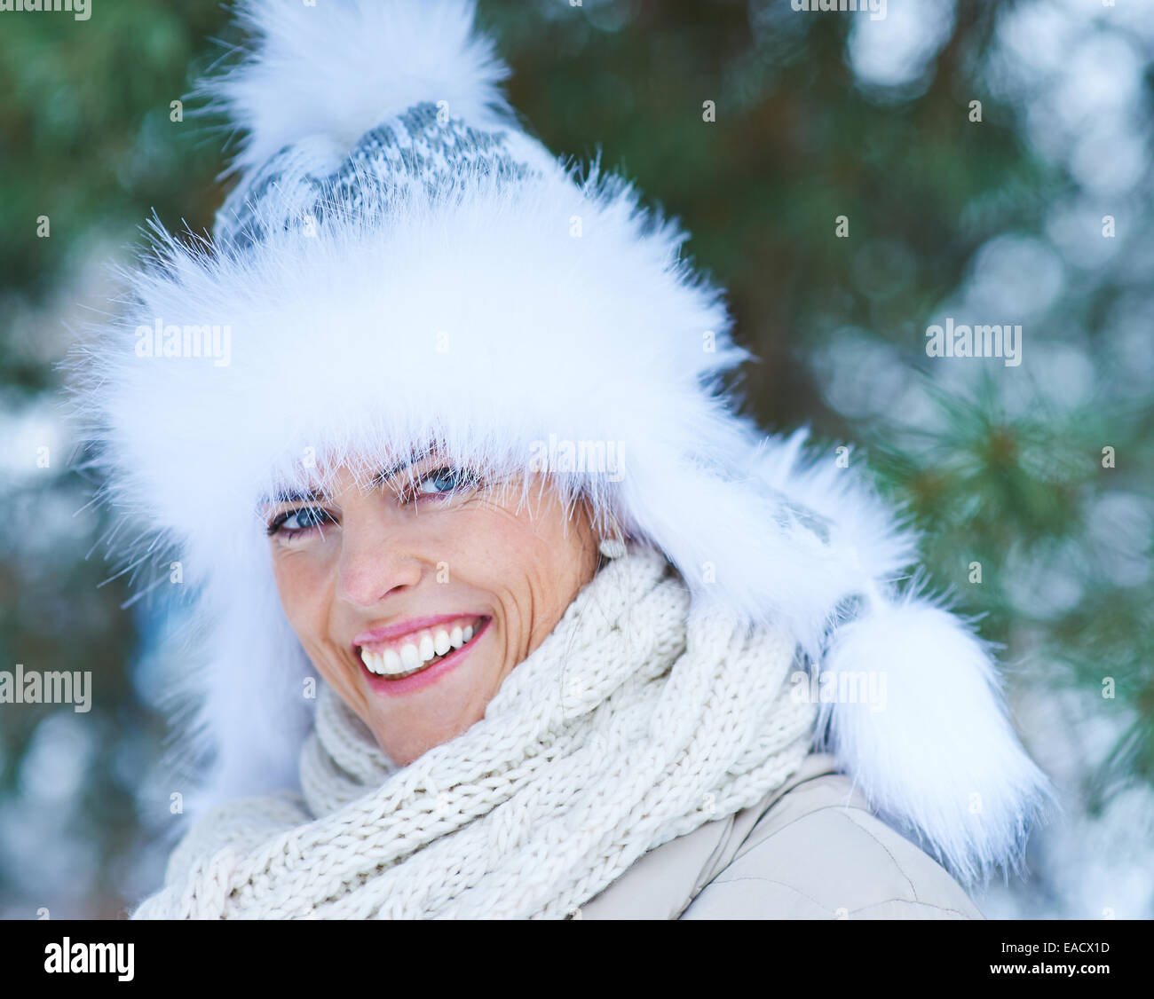 Glückliche Frau lächelnd mit Pelzmütze im Freien im winter Stockfoto