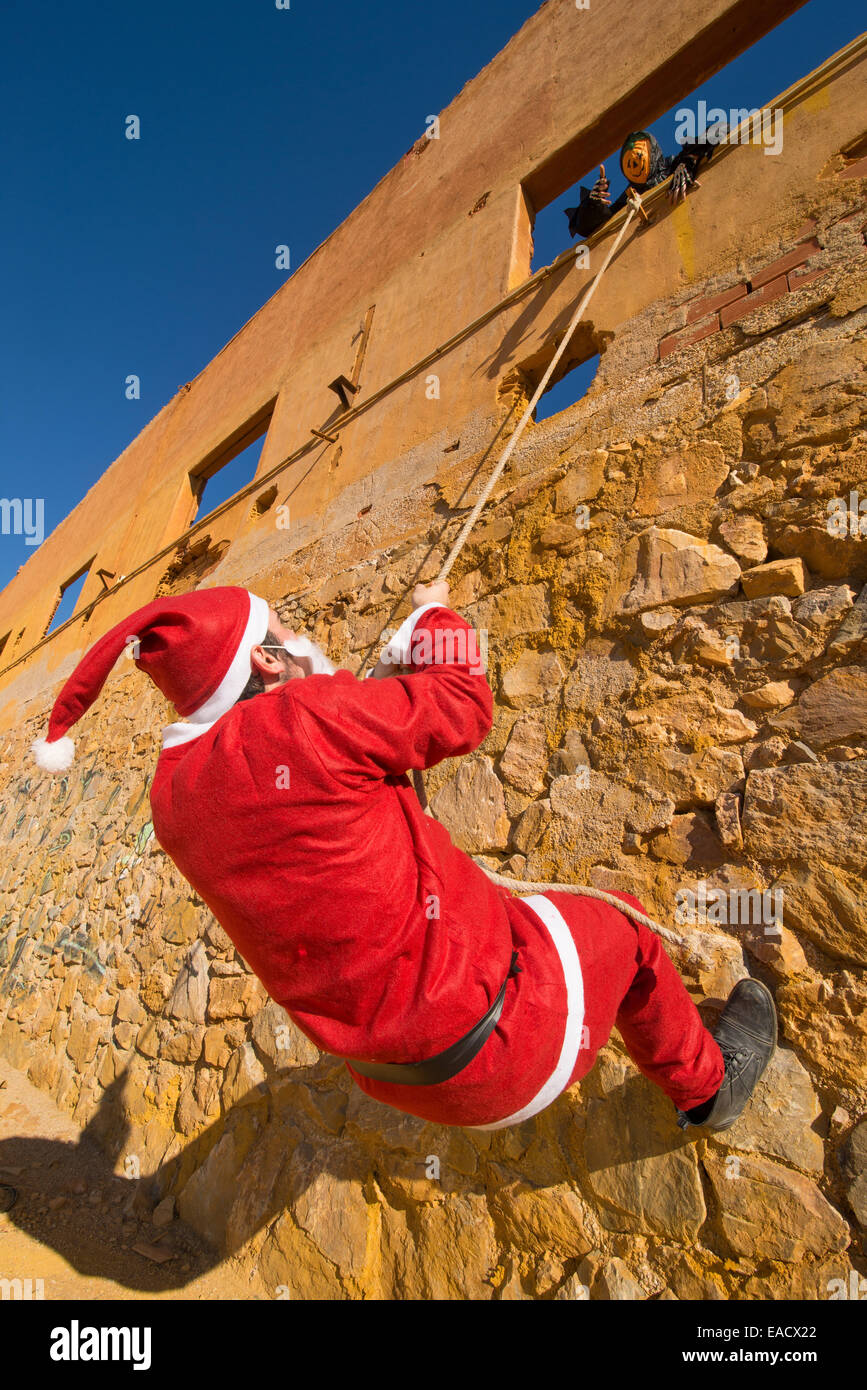 Santa, Kletterwand, während ein gruseliges Halloween-Monster auf ihn wartet Stockfoto