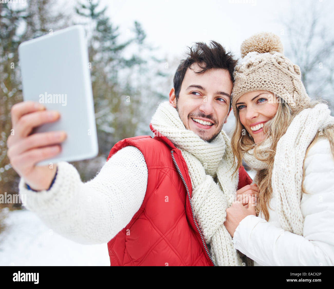 Glückliches Paar tun Selfies mit Tablet-PC in Winterlandschaft Stockfoto