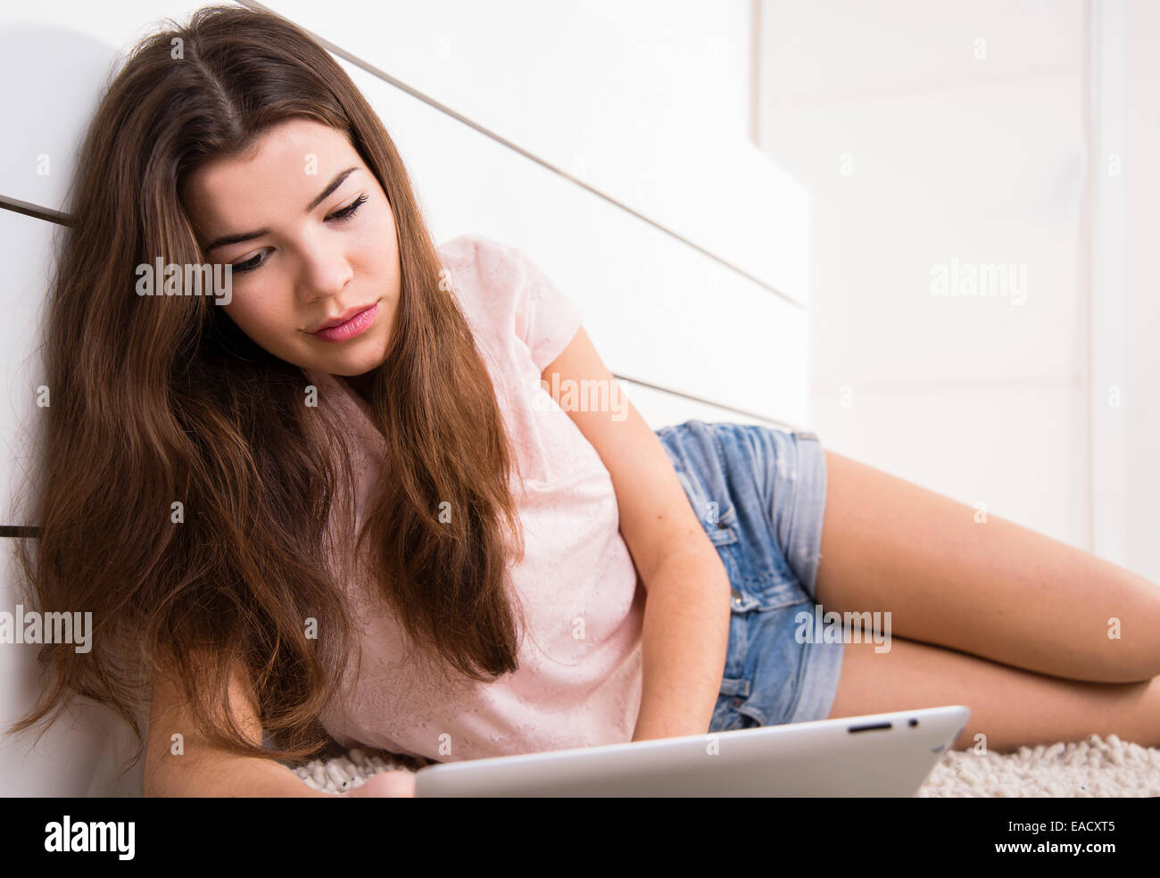 Frau auf dem Boden liegend, mit einem Tabletcomputer Stockfoto