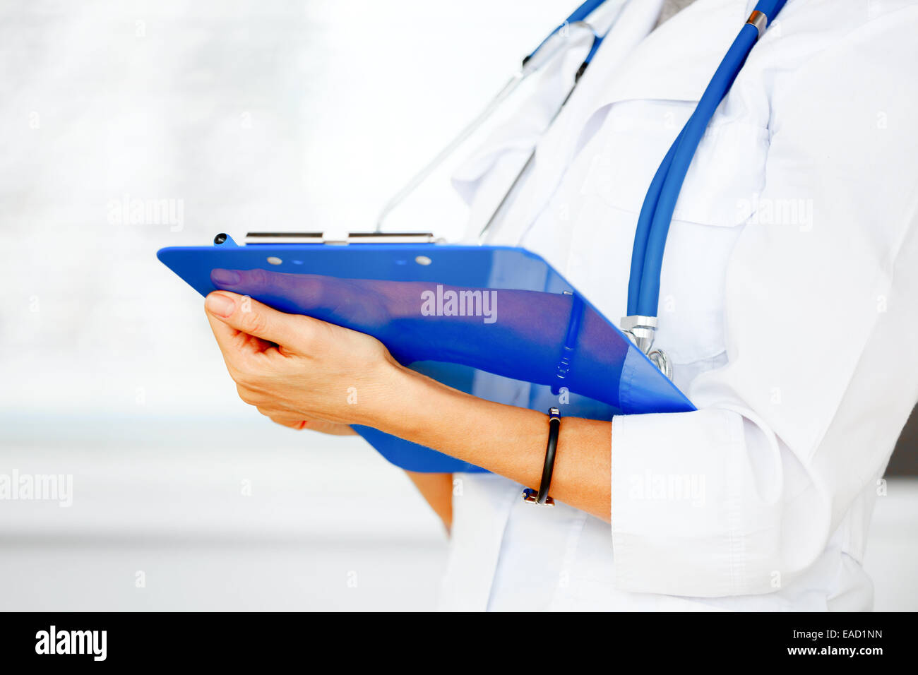 Zugeschnittenes Bild der Ärztin stehend mit Zwischenablage in ihren Händen. Stockfoto