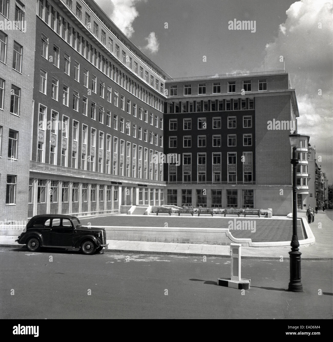 historische der 1950er Jahre Auto in der Straße außerhalb einer modernen, neu gebauten Bürokomplex, London, England. Stockfoto