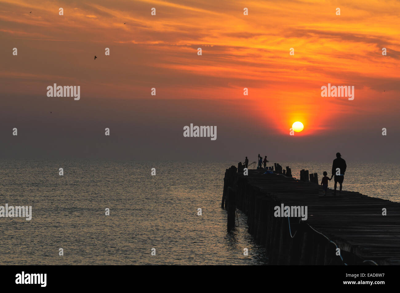 Silhouette Fischer auf die alte Holzbrücke und das Meer bei Sonnenaufgang im ländlichen Thailand. Stockfoto