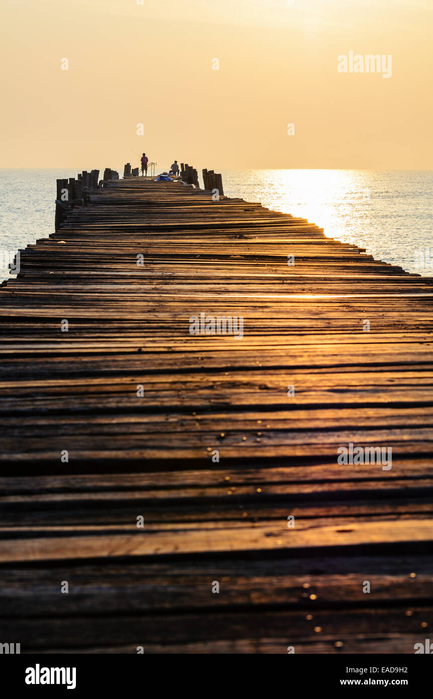 Fischer auf der alten Holzbrücke bei Sonnenaufgang im ländlichen Thailand. Stockfoto