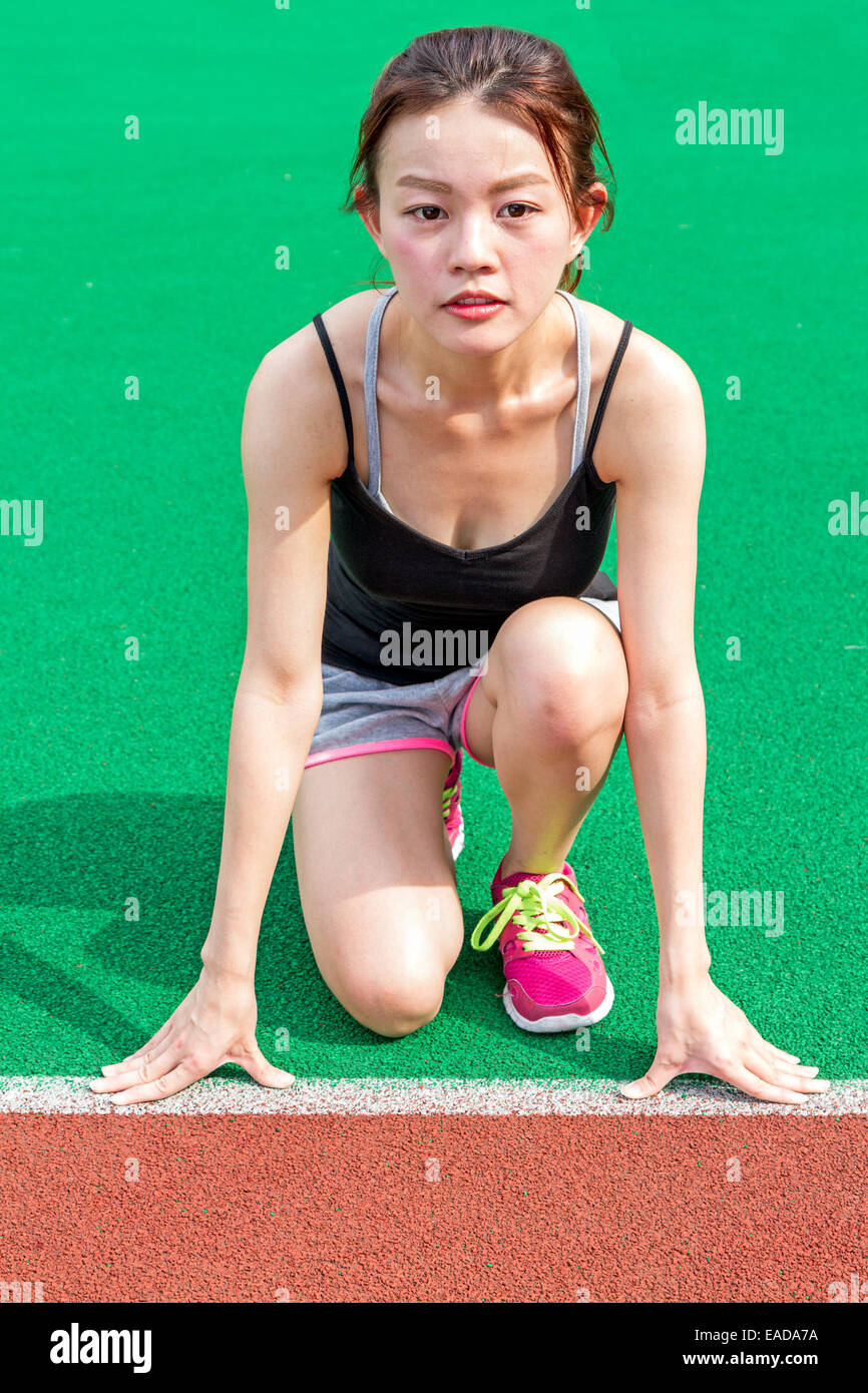 Junge chinesische Sportler in Startposition auf Rennstrecke Stockfoto