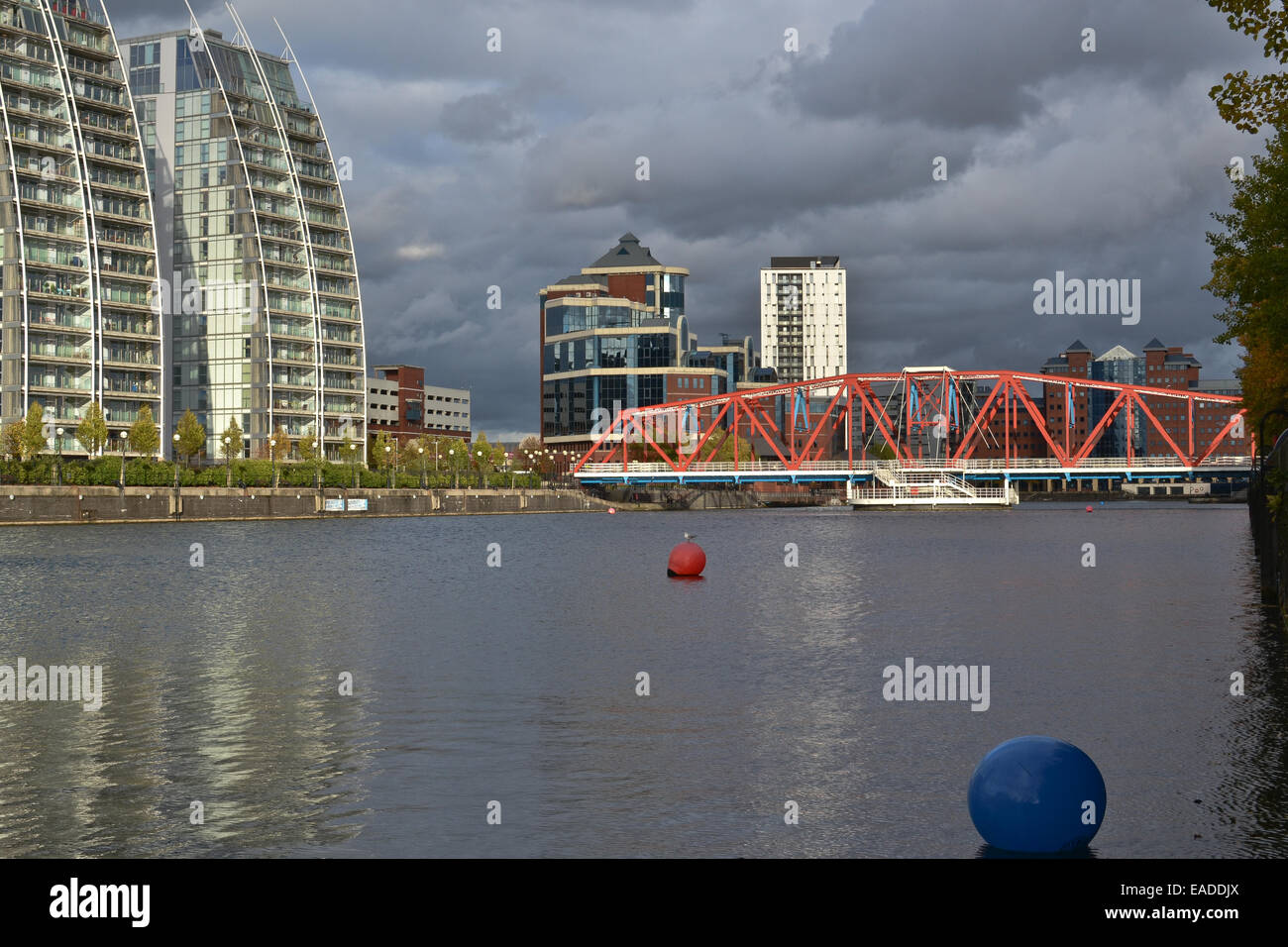 Apartments mit Blick auf das Wasser an Manchester Salford Kais, MediaCityUK, an einem hellen, sonnigen Nachmittag mit Gewitterwolken oben Stockfoto