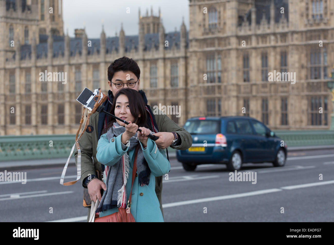 Asian paar nehmen ein Selbstporträt mit "Selfie Stick" mit dem Palace of Westminster im Hintergrund Stockfoto