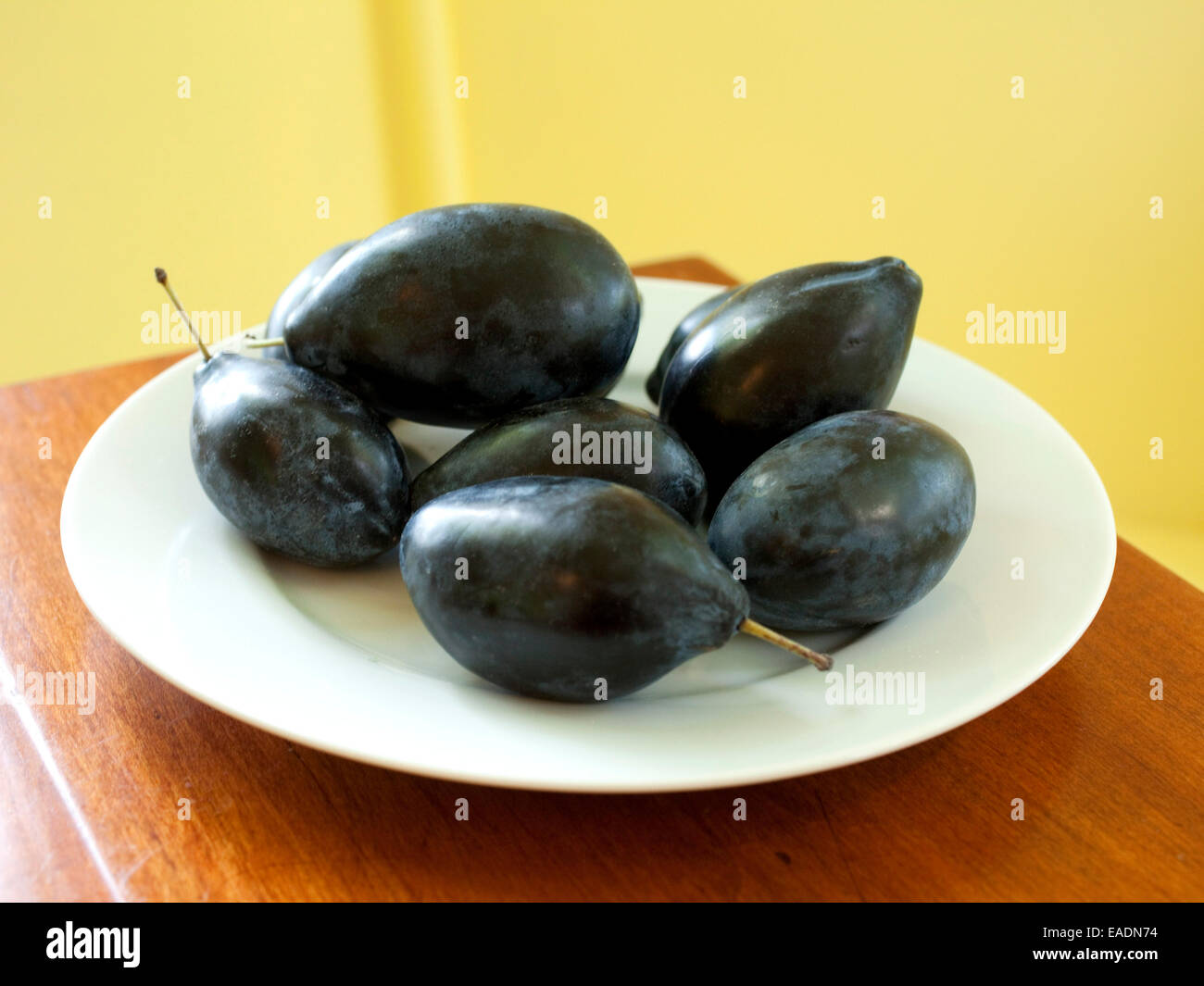 Schwarze Pflaumen auf weißen Teller In Küche Stockfoto