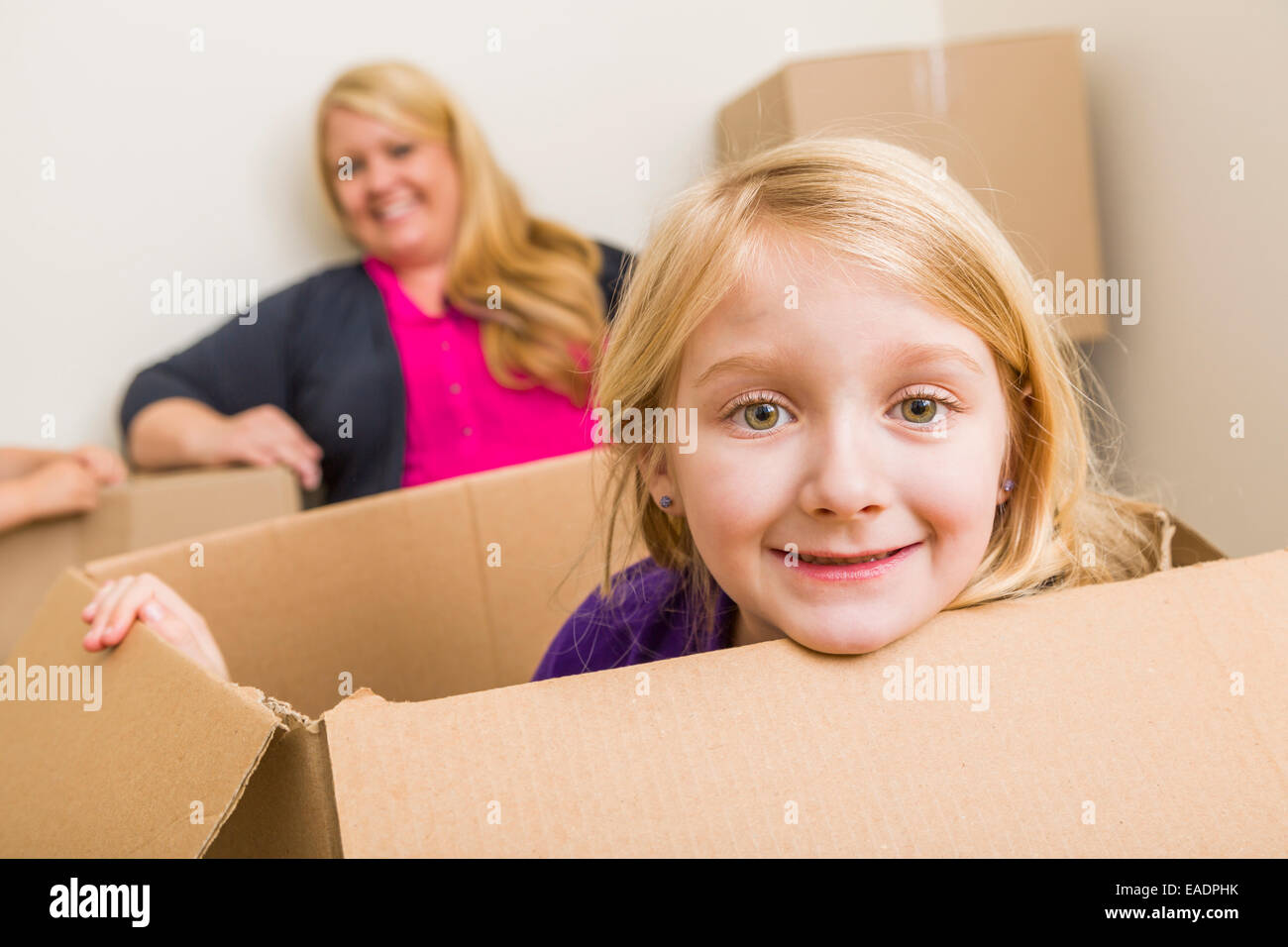Glückliche junge Mutter und Tochter Spaß mit Umzugskartons. Stockfoto