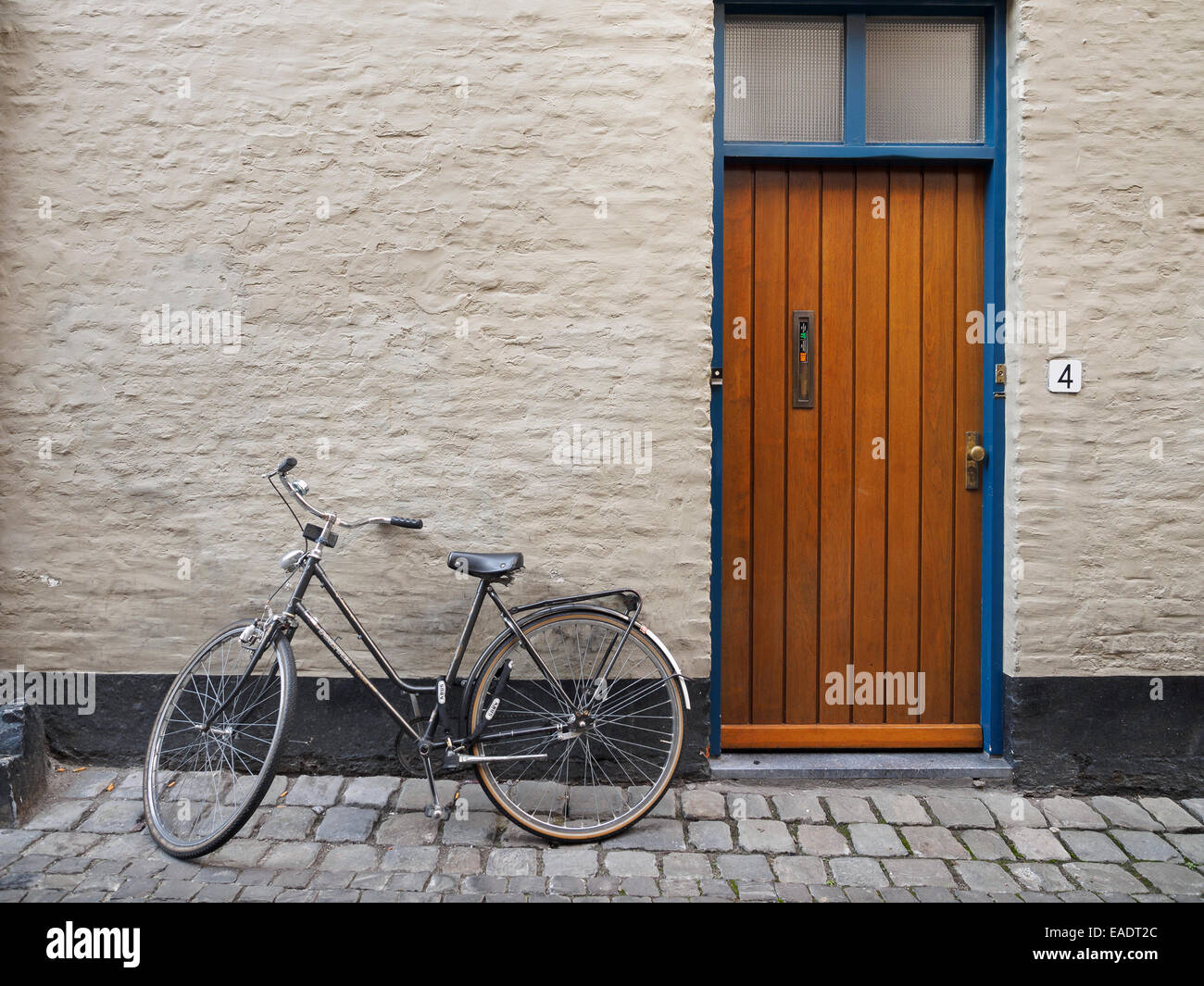 Oldtimer Fahrrad lehnt an einer Wand neben einer Haustür Stockfoto