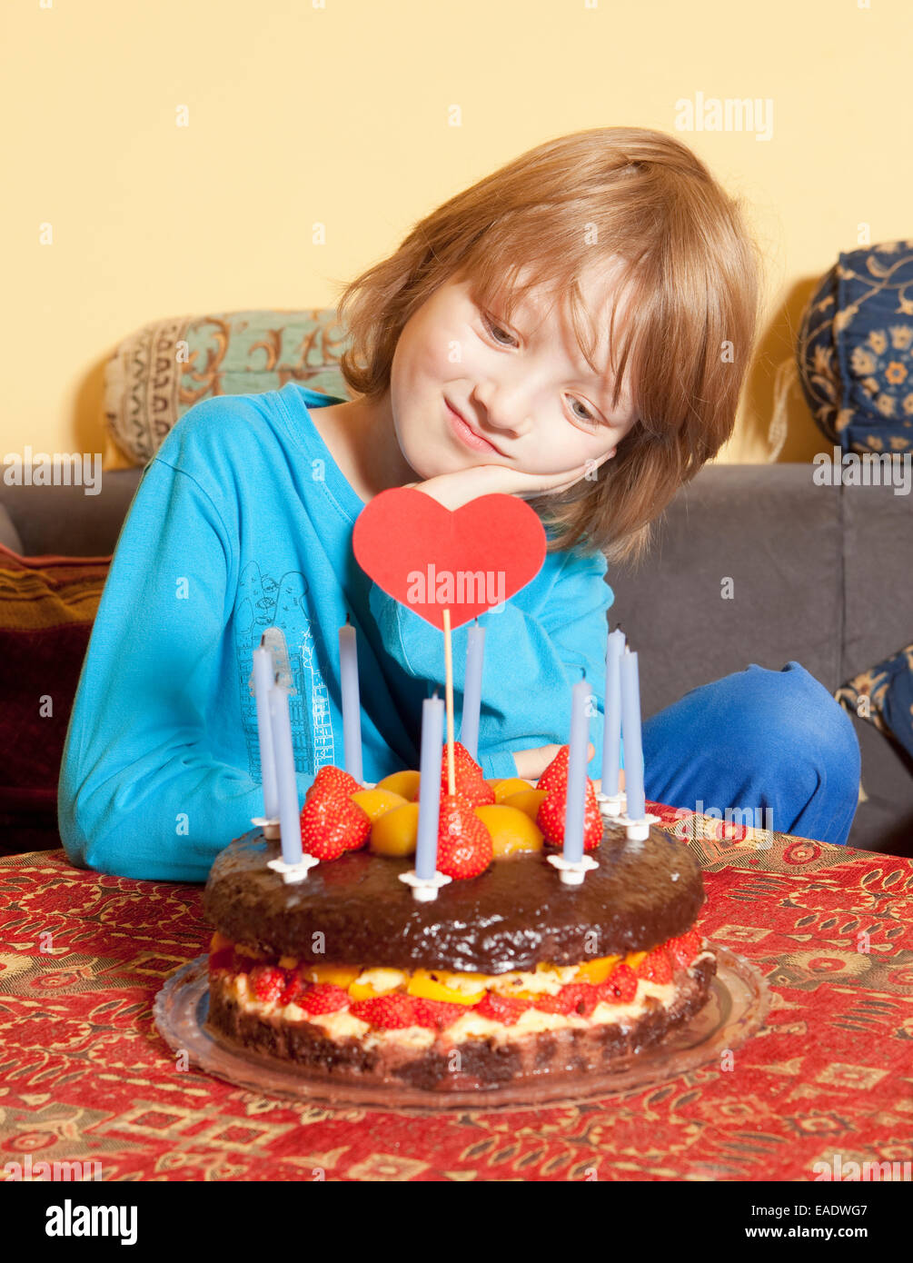 Junge mit blonden Haaren mit Blick auf seine Geburtstagstorte Stockfoto