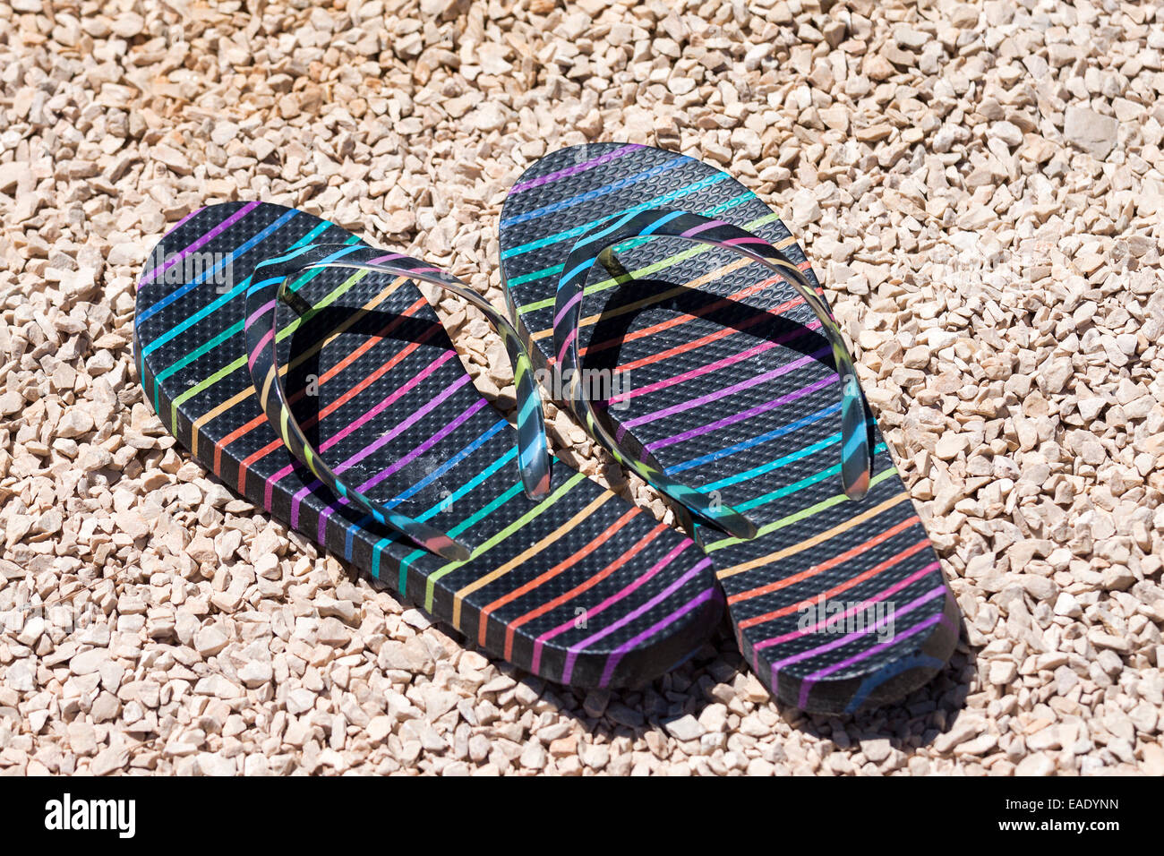 Gestreifte Flip-Flops am Strand im sonnigen Tag Stockfoto