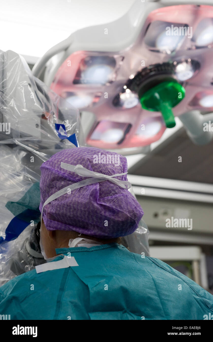 Ein Chirurg wird durch ein Mikroskop während einer Operation in einem Krankenhaus auf der Suche Stockfoto