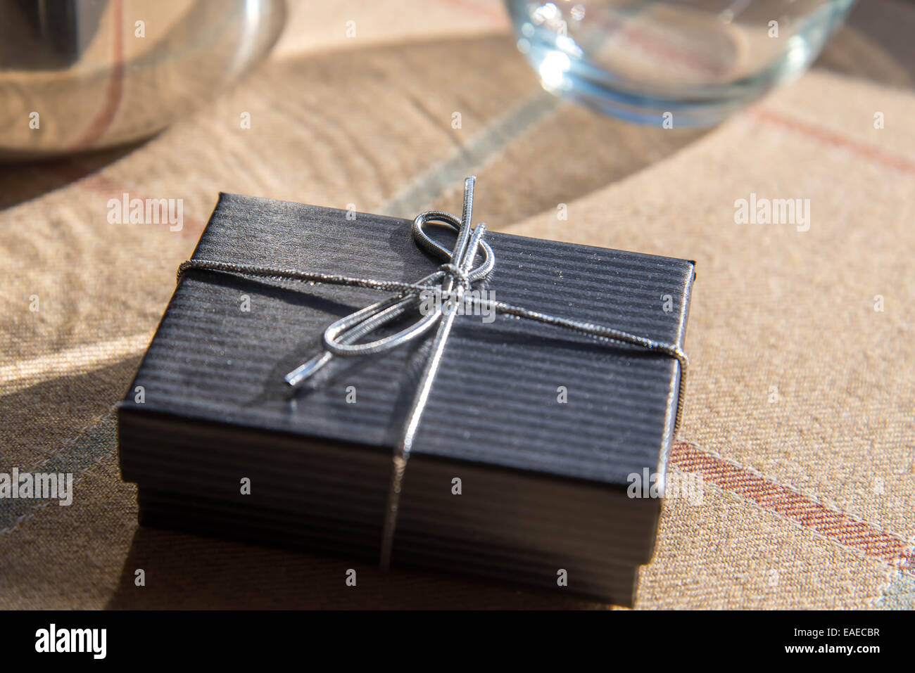 kleine schwarze Schmuck Geschenk-Box mit einem silbernen Bogen im morgendlichen Sonnenlicht Stockfoto