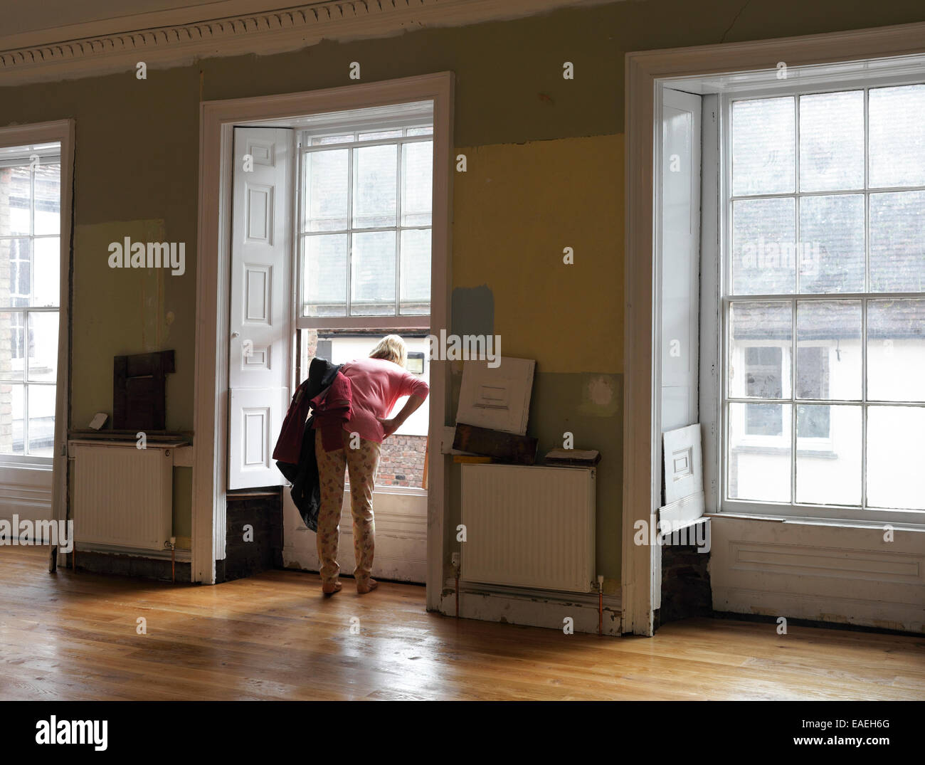 Eine Frau, die aus einem Fenster bei Hanse Haus, King's Lynn, Norfolk während der Renovierung des Gebäudes. Stockfoto