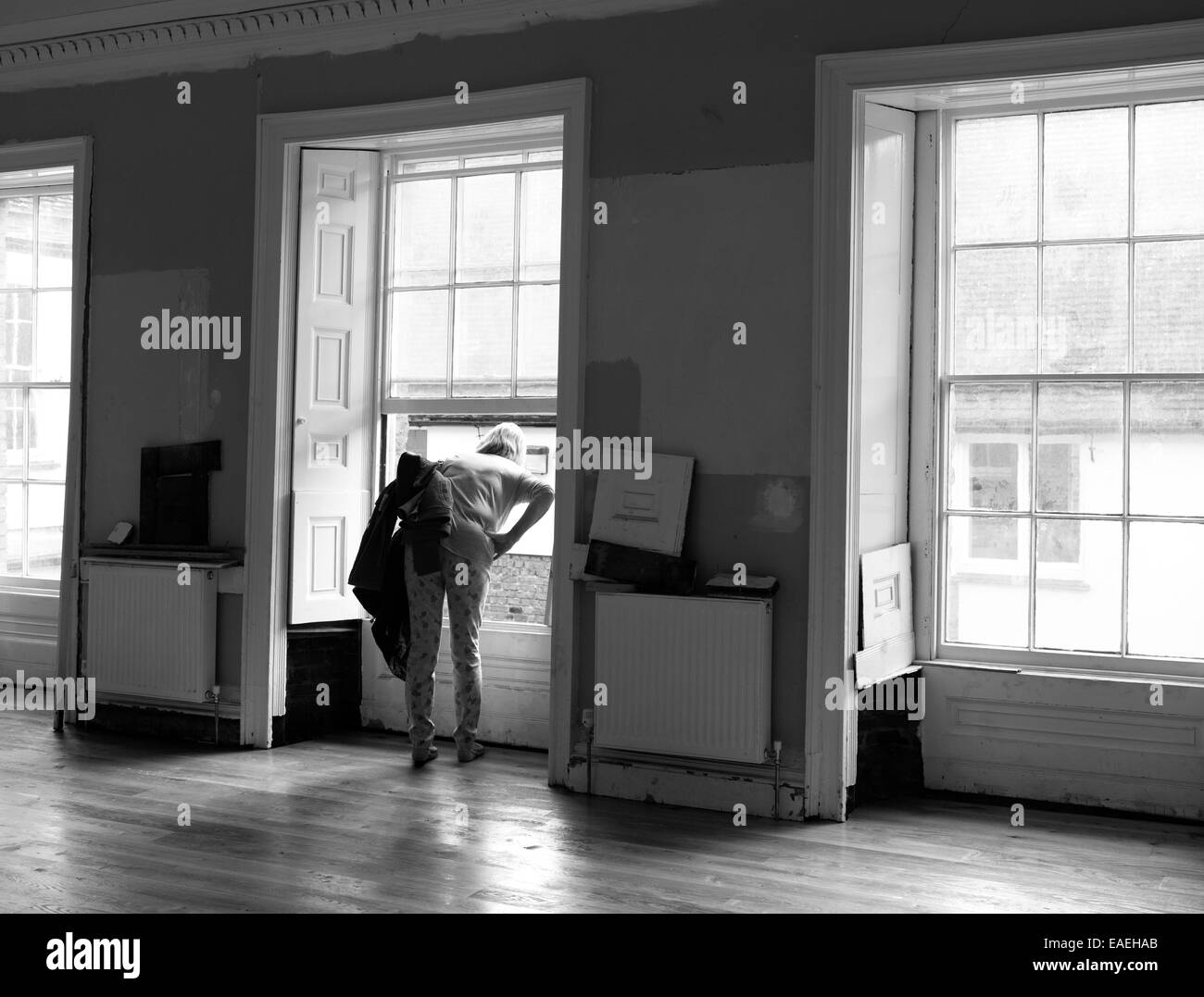 Eine Frau, die aus einem Fenster bei Hanse Haus, King's Lynn, Norfolk während der Renovierung des Gebäudes. Stockfoto
