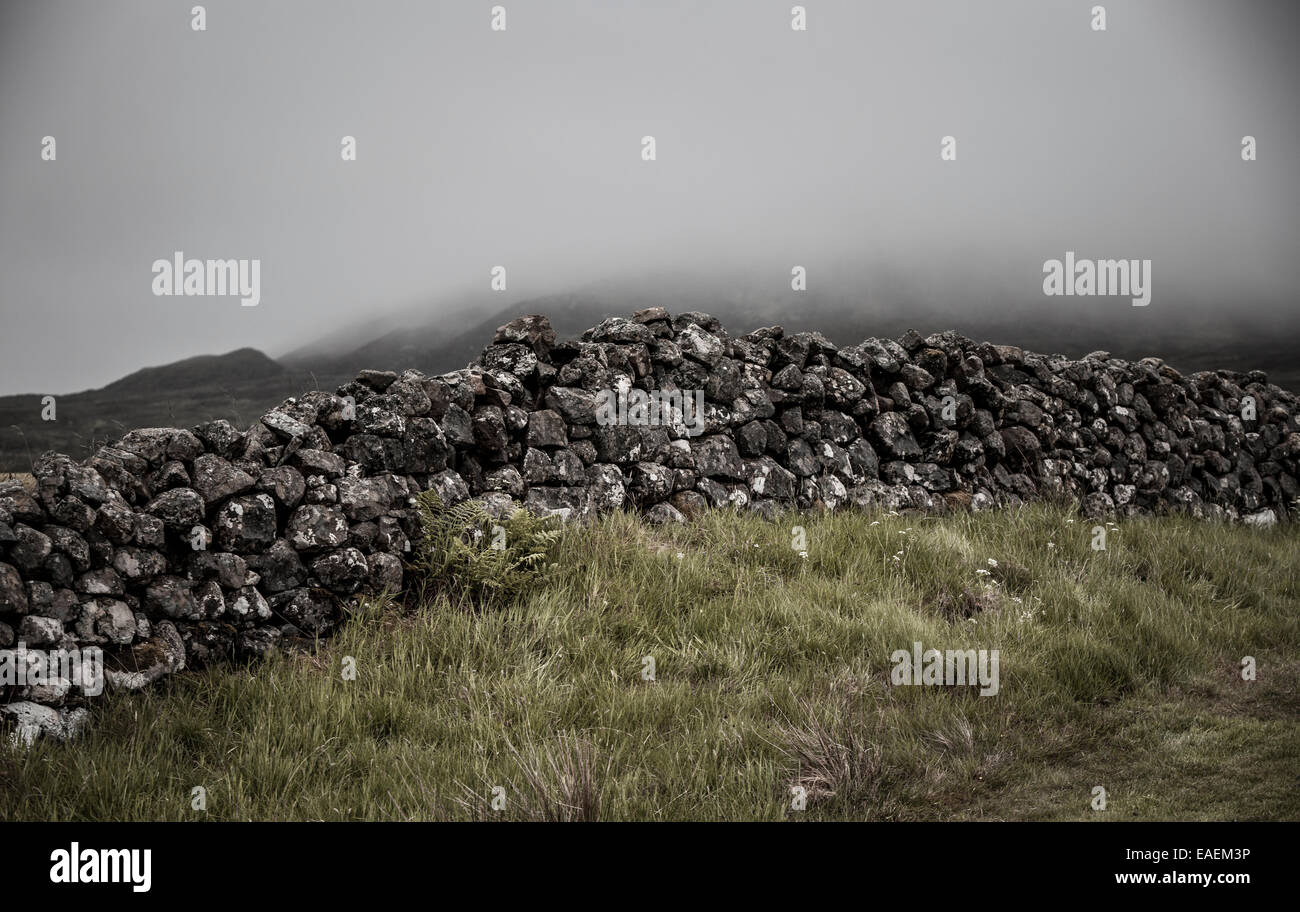 Ein stimmungsvoller Regen durchnässt Steinmauer im schottischen Hochland Stockfoto