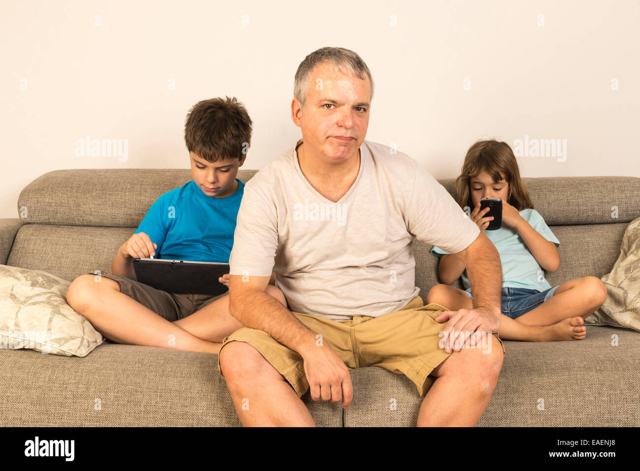 Kinder sitzen auf dem Sofa spielen, während sein Vater nicht wissen, was zu tun Stockfoto