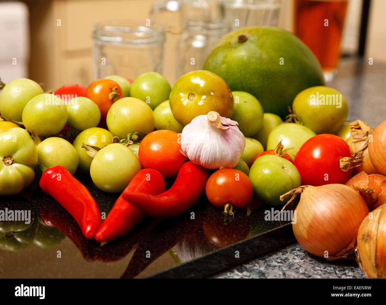 Grüne Tomaten, etwas rot, Zwiebeln, Knoblauch, roten Chilis und nur um ein wenig anders, eine Mango in der heimischen Küche Stockfoto