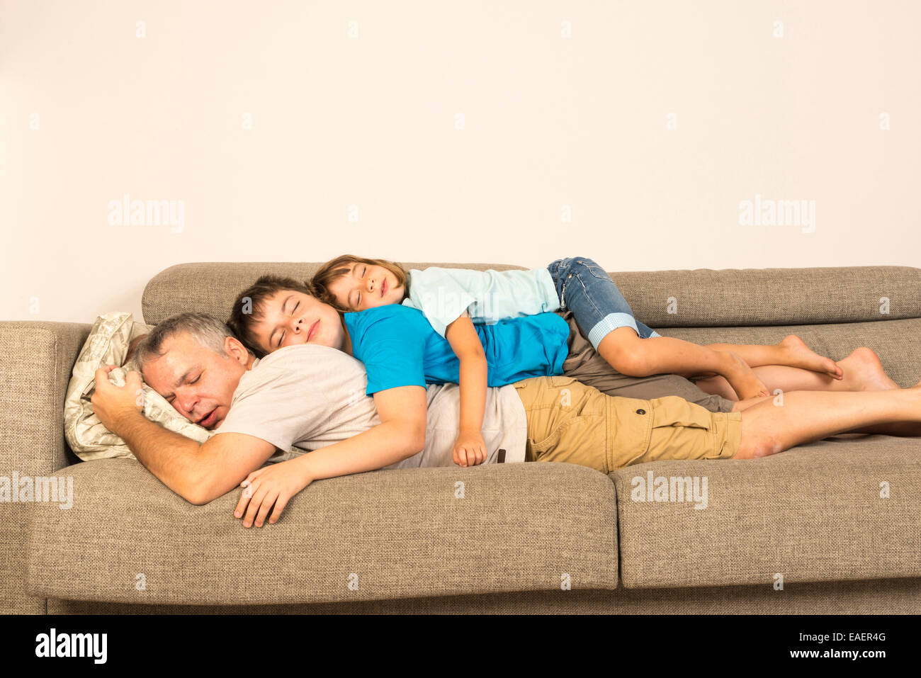 Vater und Sohn auf dem Sofa ausgestreckt übereinander Stockfoto