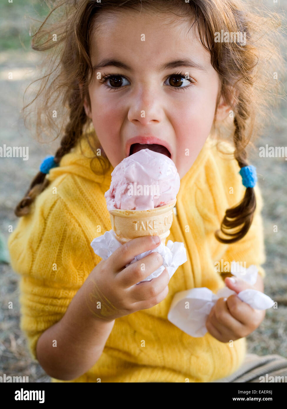 junges Mädchen essen Erdbeereis aus einem Kegel Stockfoto