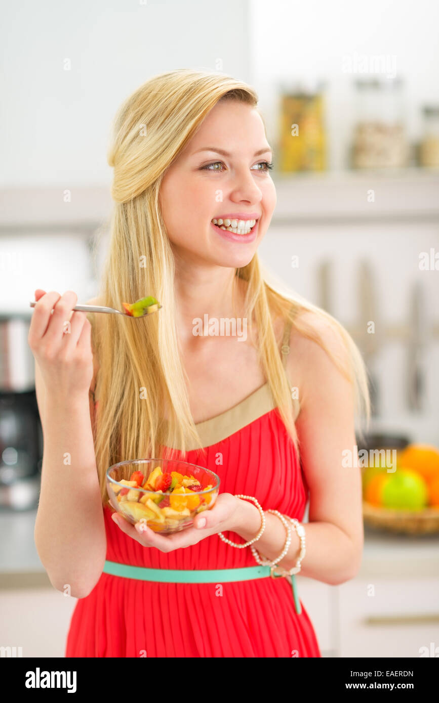 Glückliche junge Frau essen Obst Salat in Küche Stockfoto