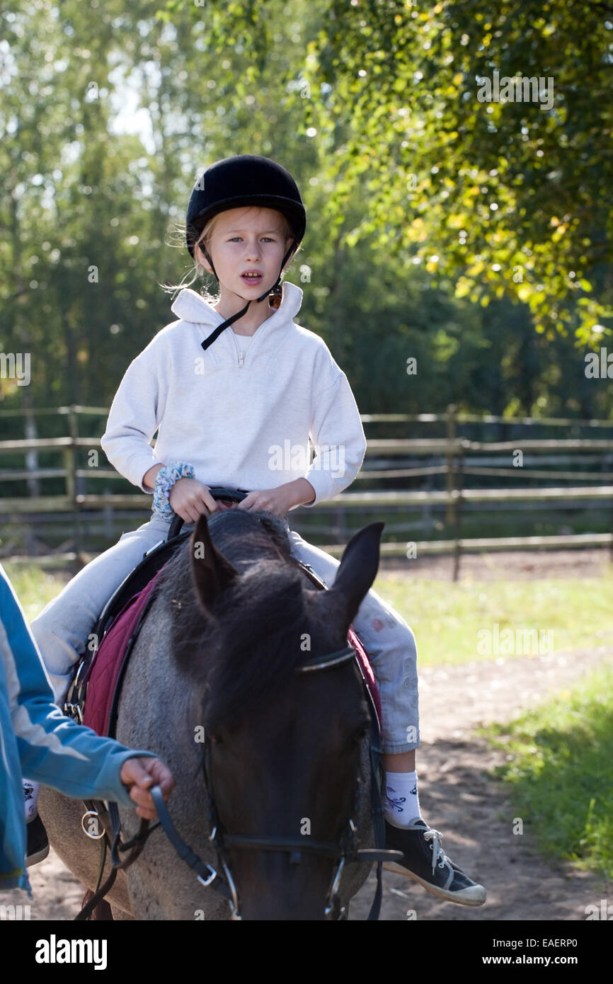 kleines Mädchen in der Jockey-Kappe Reiten auf outdoor-Sommer Natur Hintergrund Stockfoto