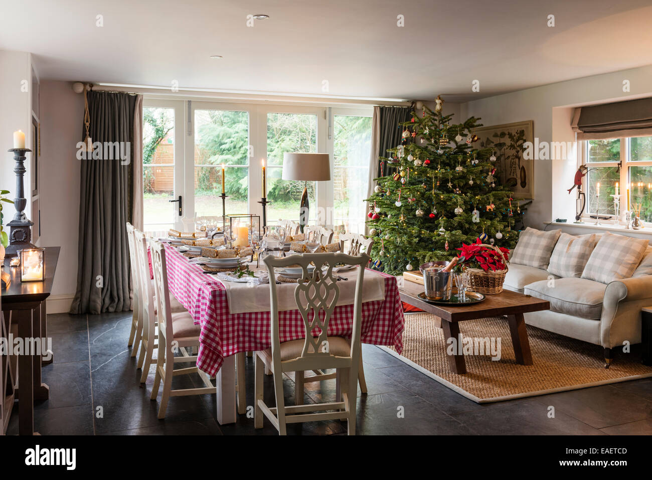 Tabelle für Weihnachtsessen im Wohnbereich mit geschmückten Baum, antikes Sofa und Seegras-Matte gelegt. Stockfoto