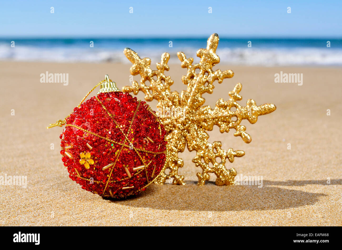 eine Weihnachtskugel und einen Stern auf dem Sand des Strandes Stockfoto