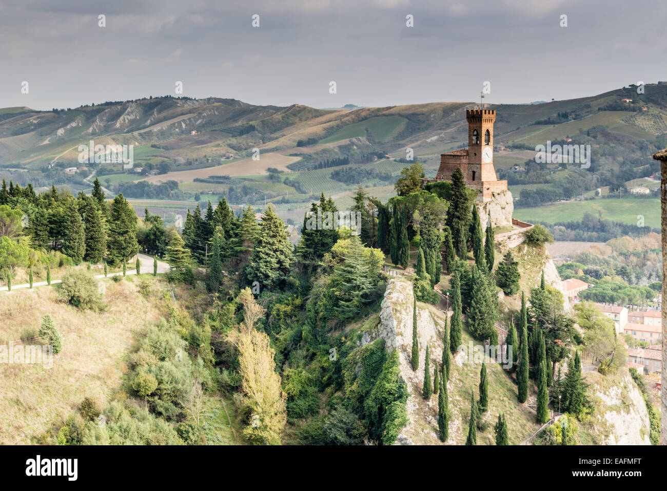Der mittelalterliche Uhrturm, umgeben von Zypressen und anderen Bäumen, aus den Felsen von Brisighella in Emilia Romagna, Italien betrachtet. Stockfoto