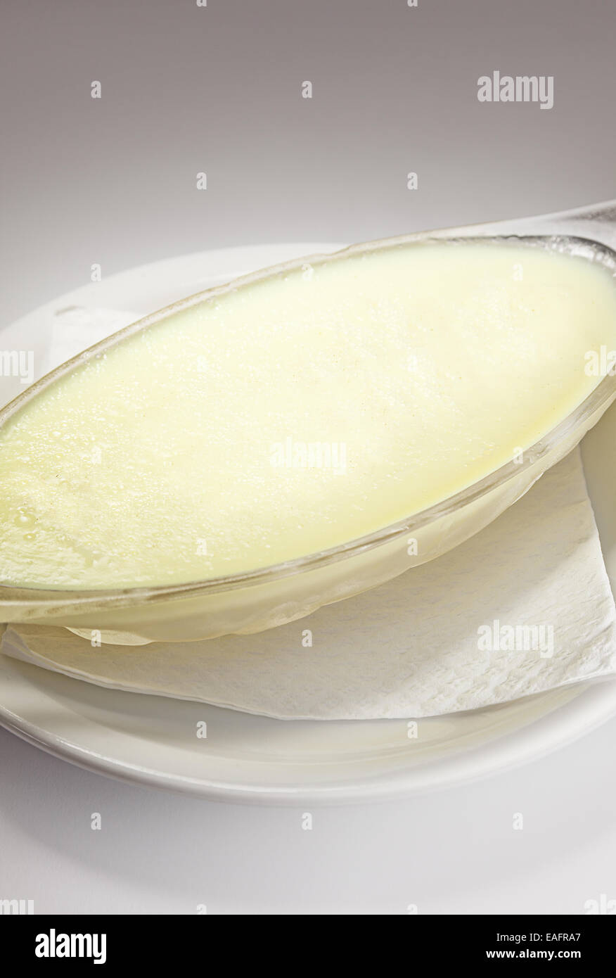 Milchreis in Glasschale auf weißen Teller mit Taschentuch. Stockfoto
