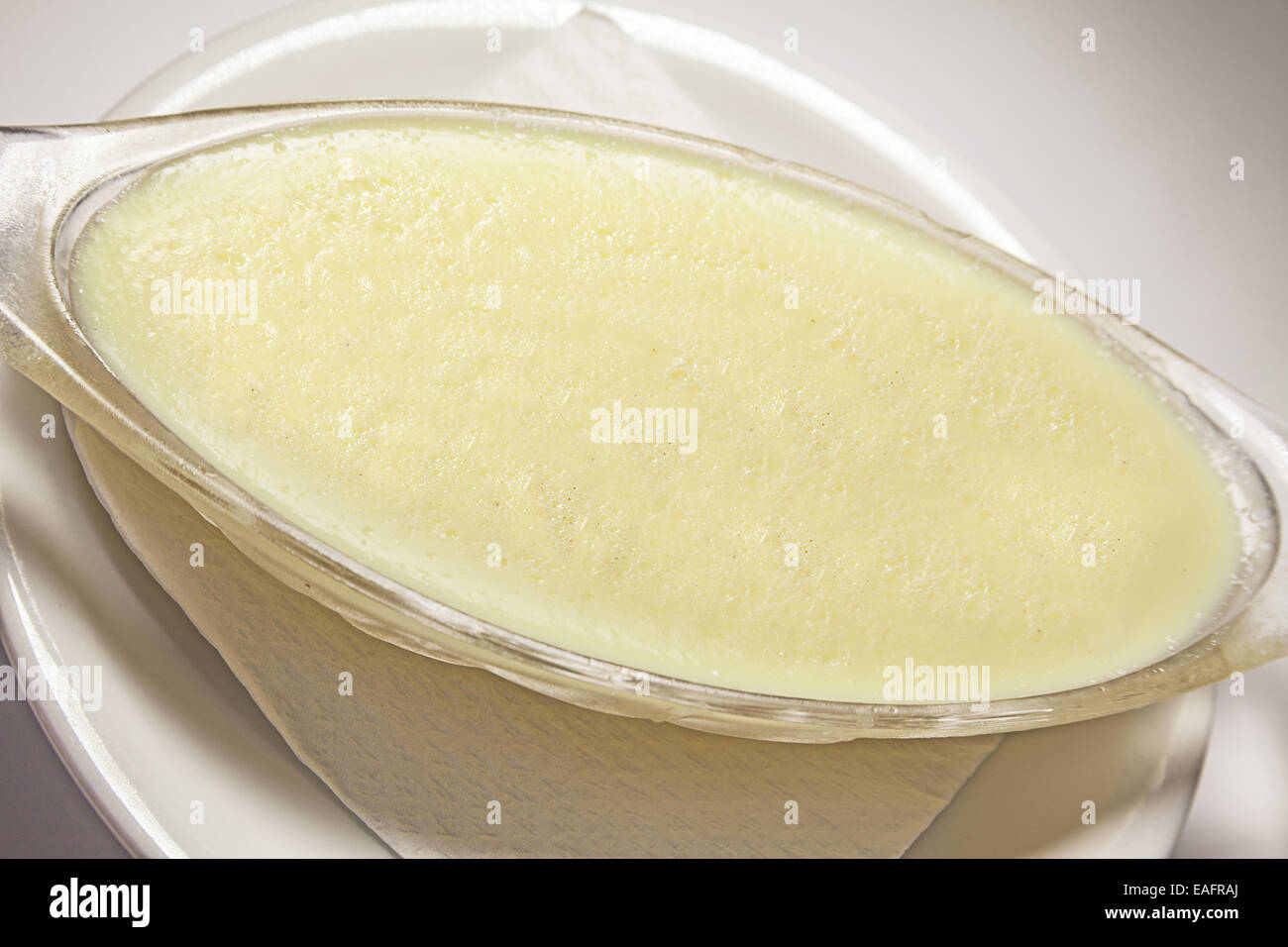 Milchreis in Glasschale auf weißen Teller mit Taschentuch. Stockfoto