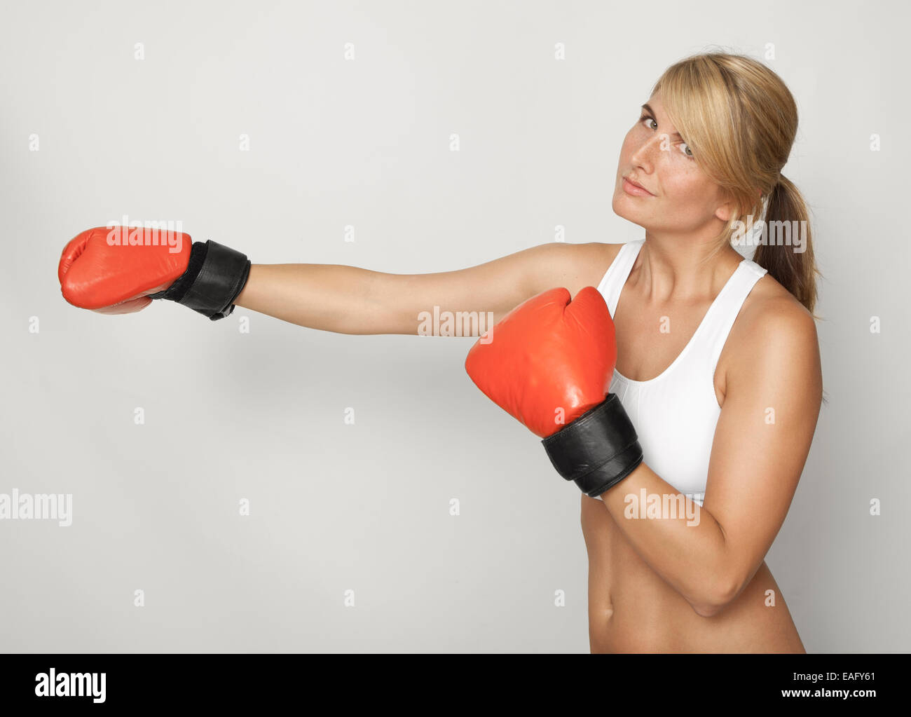 eine sportliche junge Frau mit roten Boxhandschuhe, weißer Hintergrund Stockfoto