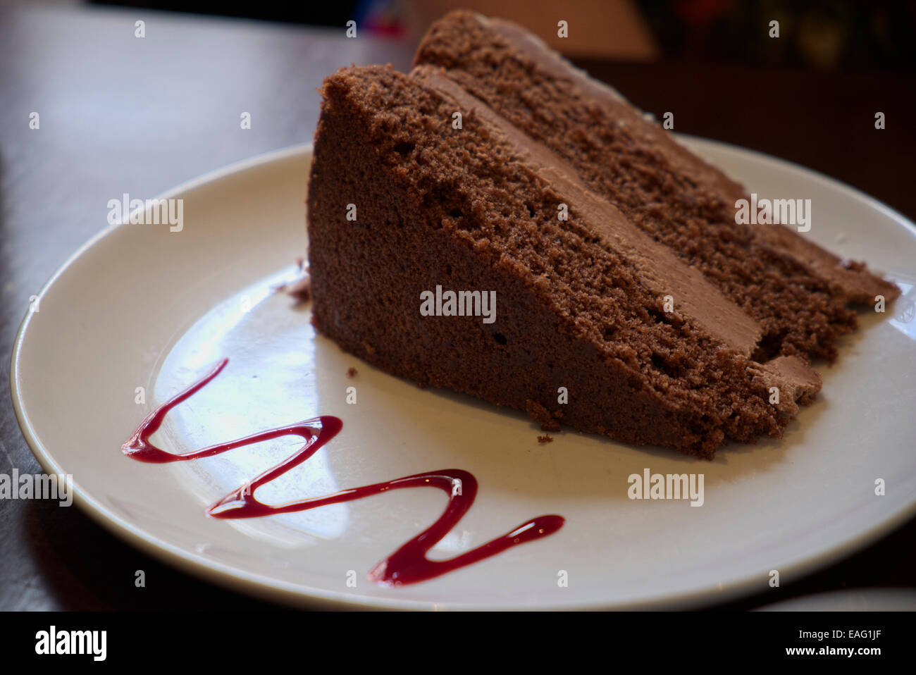 Stück Schokolade Kuchen serviert auf einem Teller mit roter Sauce Derbyshire England Stockfoto