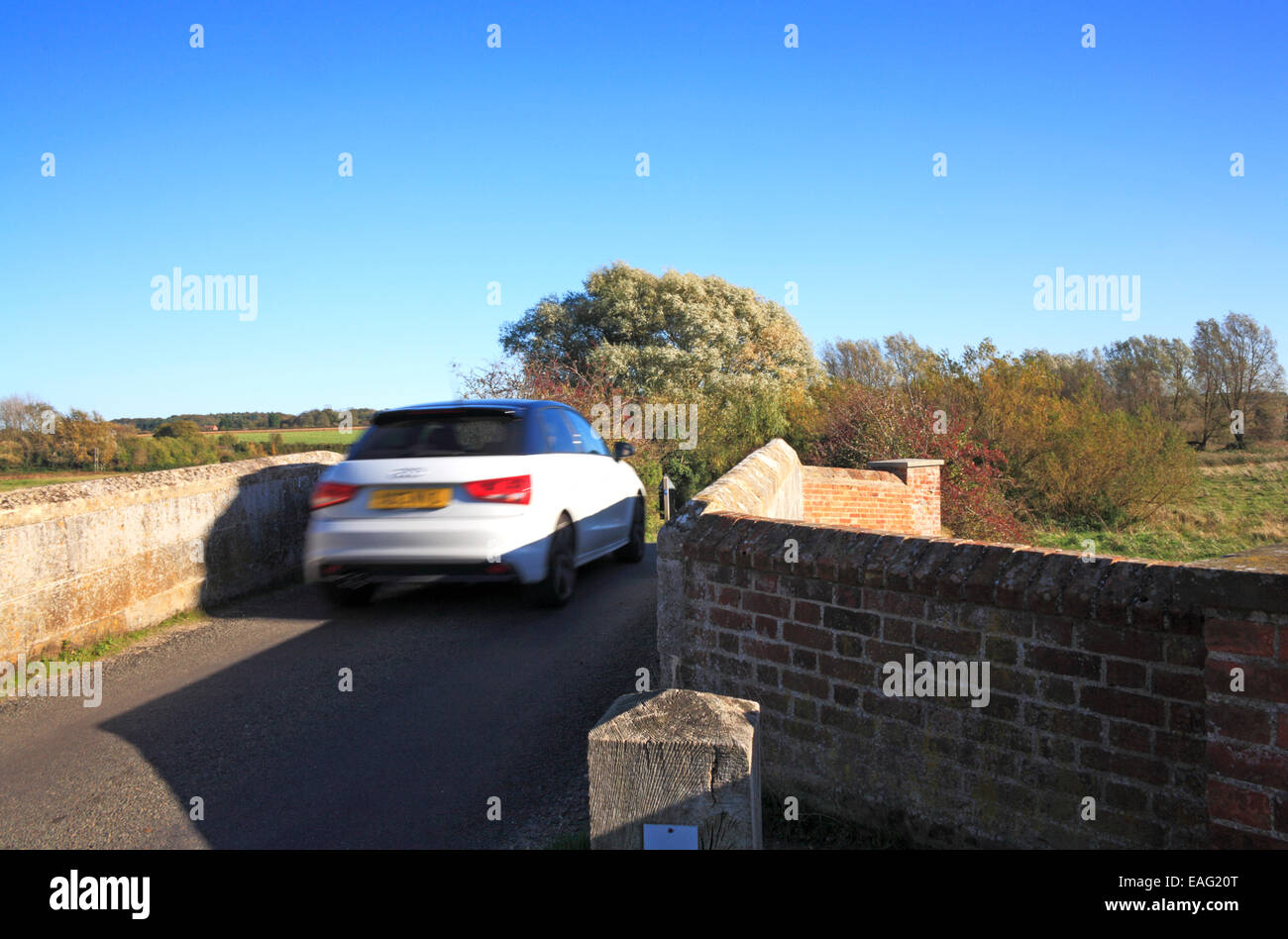 Ein Auto über eine schmale mittelalterliche bucklige Brücke in Wiveton, Norfolk, England, Vereinigtes Königreich. Stockfoto