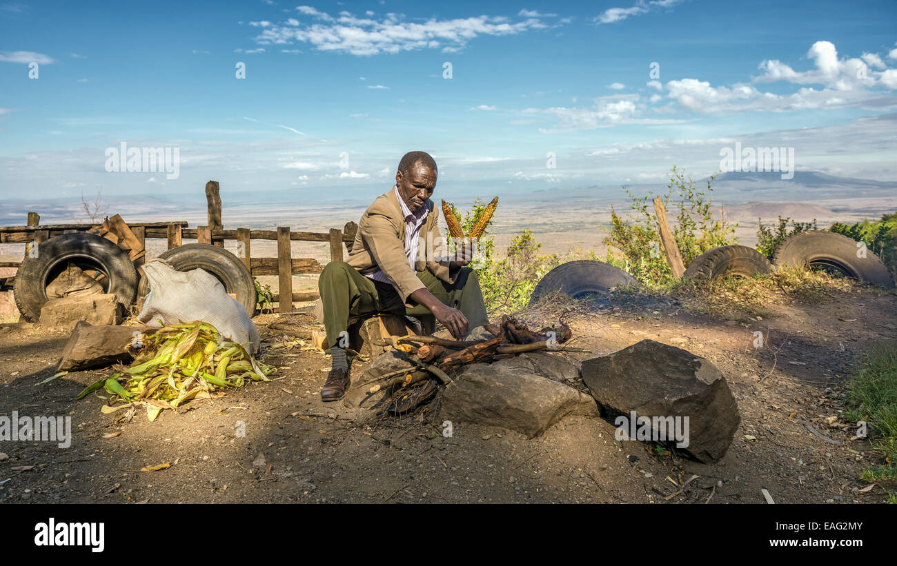 Afrikanischer Mann in einem Anzug verkauft Mais an der Kamandura Mai Mahiu Narok-Straße in der Nähe von Great Rift Valley in Kenia, Afrika Stockfoto