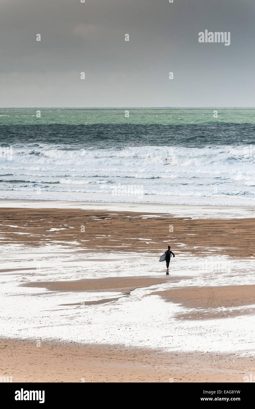 Ein einsamer Surfer zu Fuß auf Fistral Beach in Newquay, Cornwall. Stockfoto